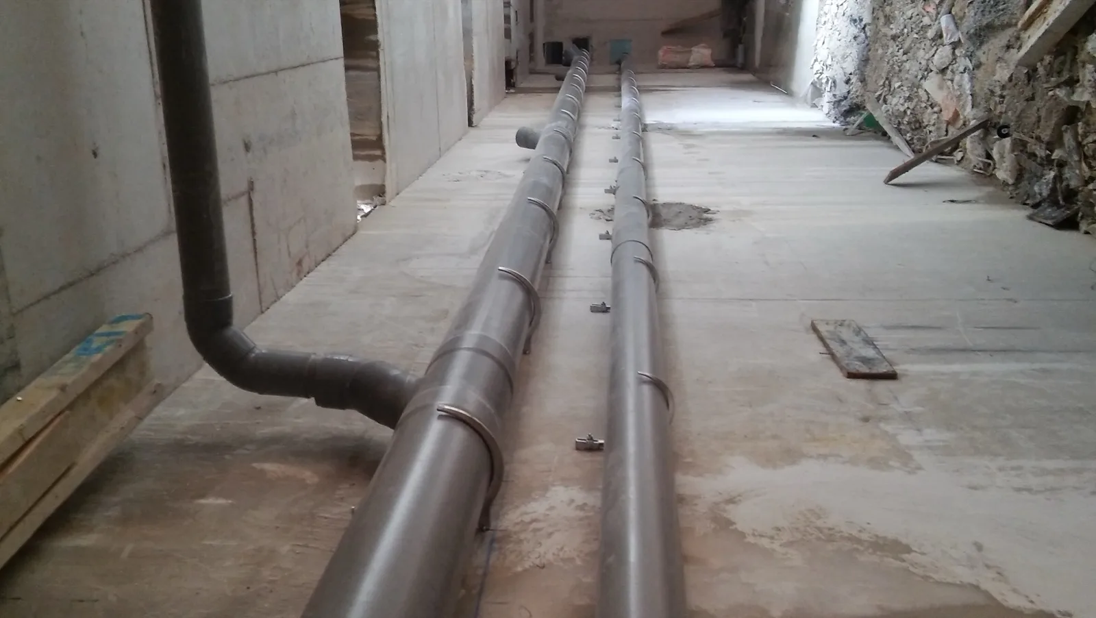 Deux collecteurs PVC superposés sur supports corbeau 101 le long d'une paroi béton