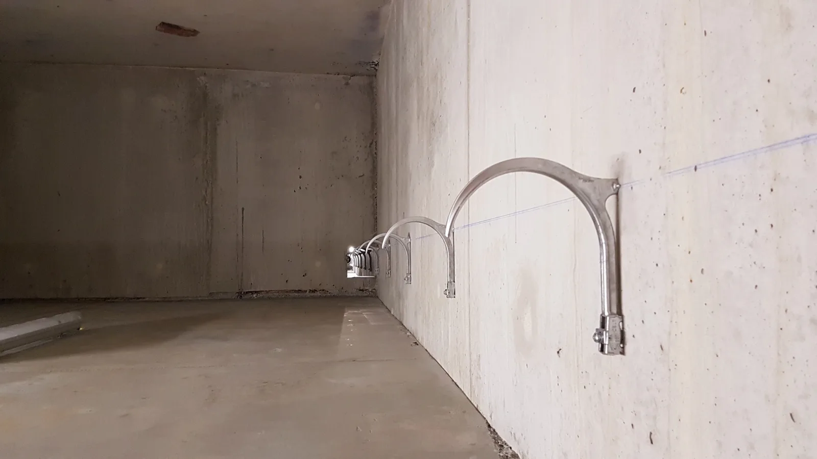 Supports corbeau aluminium posés en série sur un voile béton après traçage, avant la pose de la canalisation