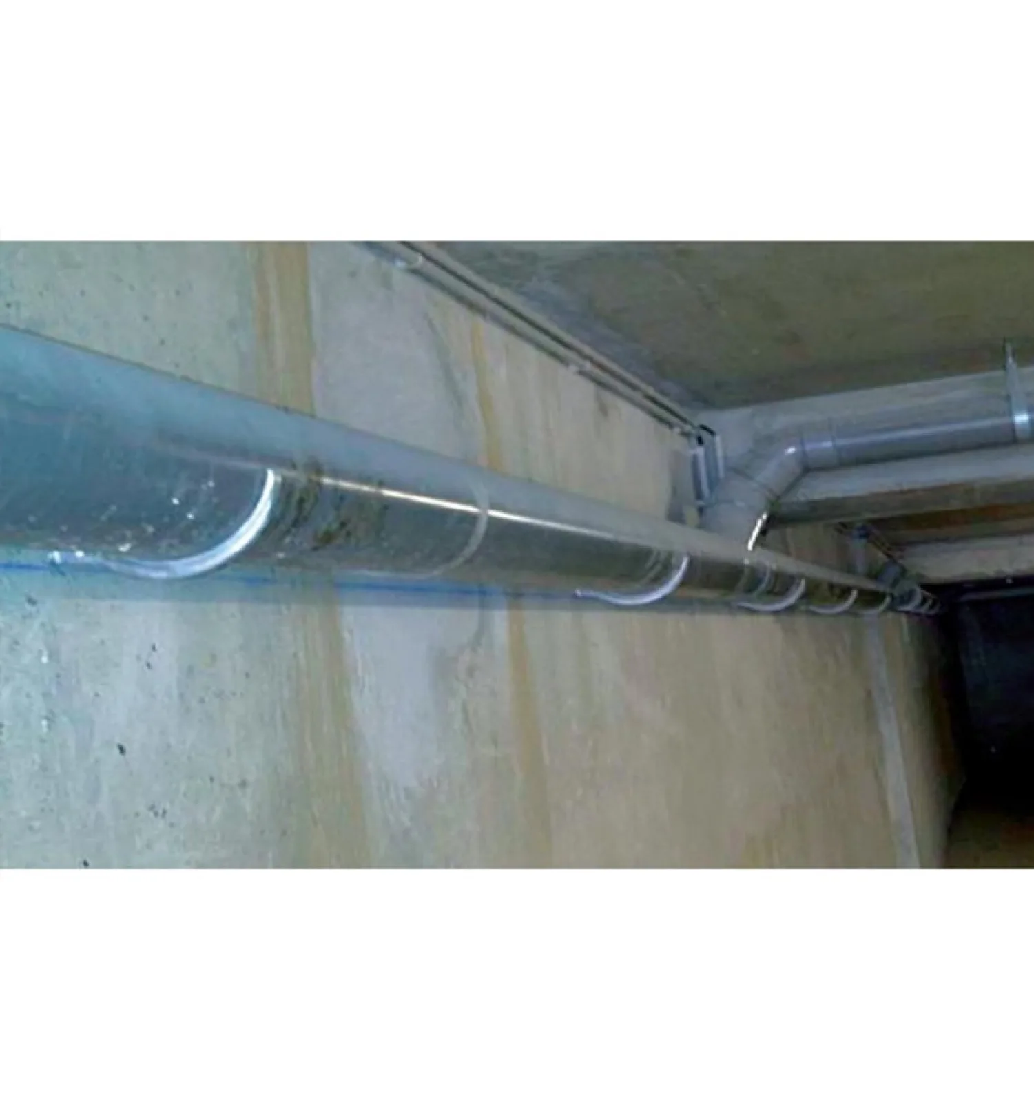 Canalisation PVC posée sur supports corbeau le long d'un mur béton