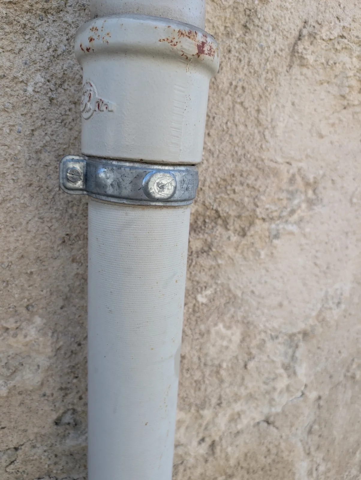 Gros plan d'un collier de descente en acier galvanisé serré sous un dauphin en fonte